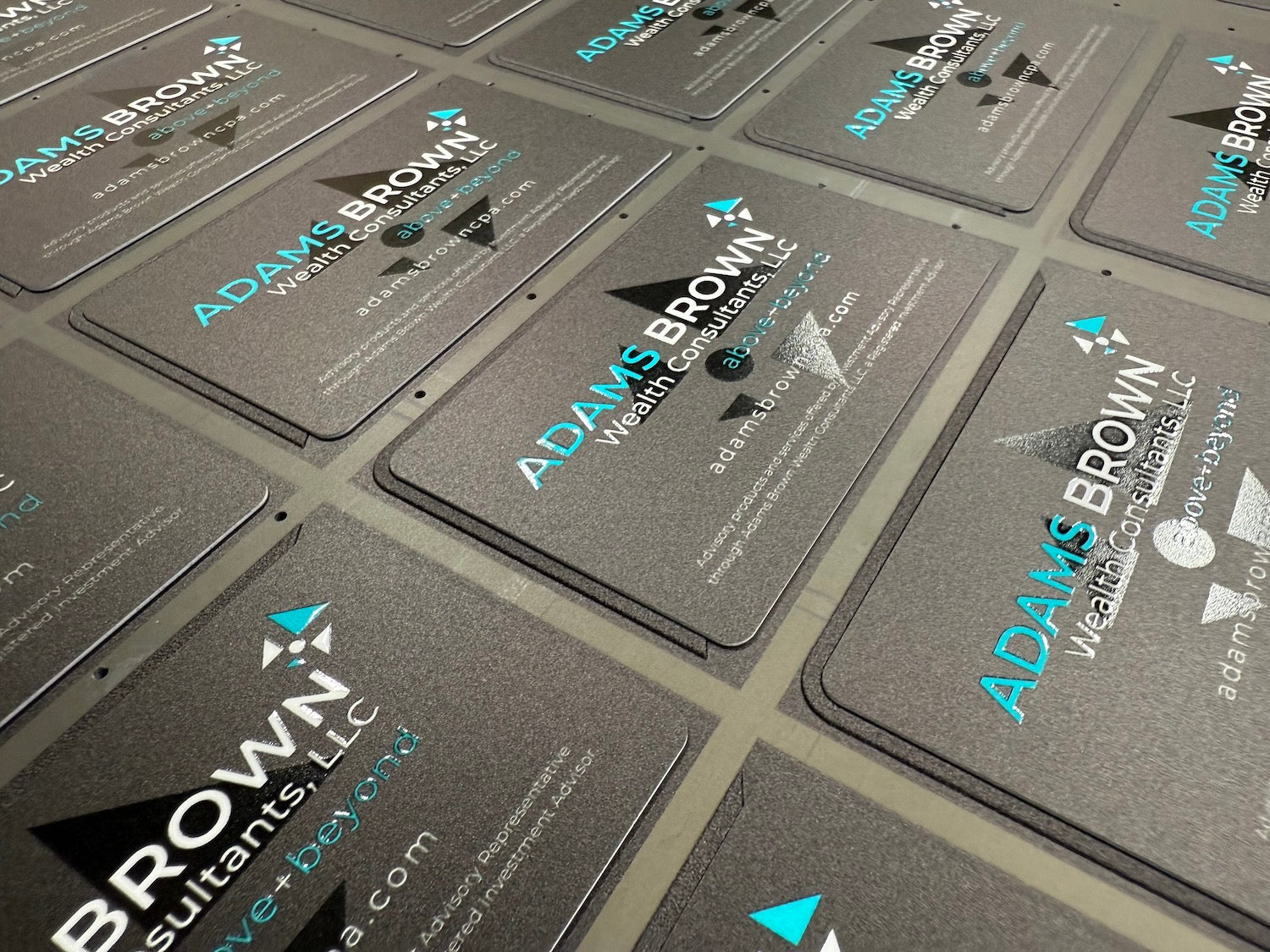 Multiple business cards with 'Adams Brown Consultants LLC' branding on a gray background.