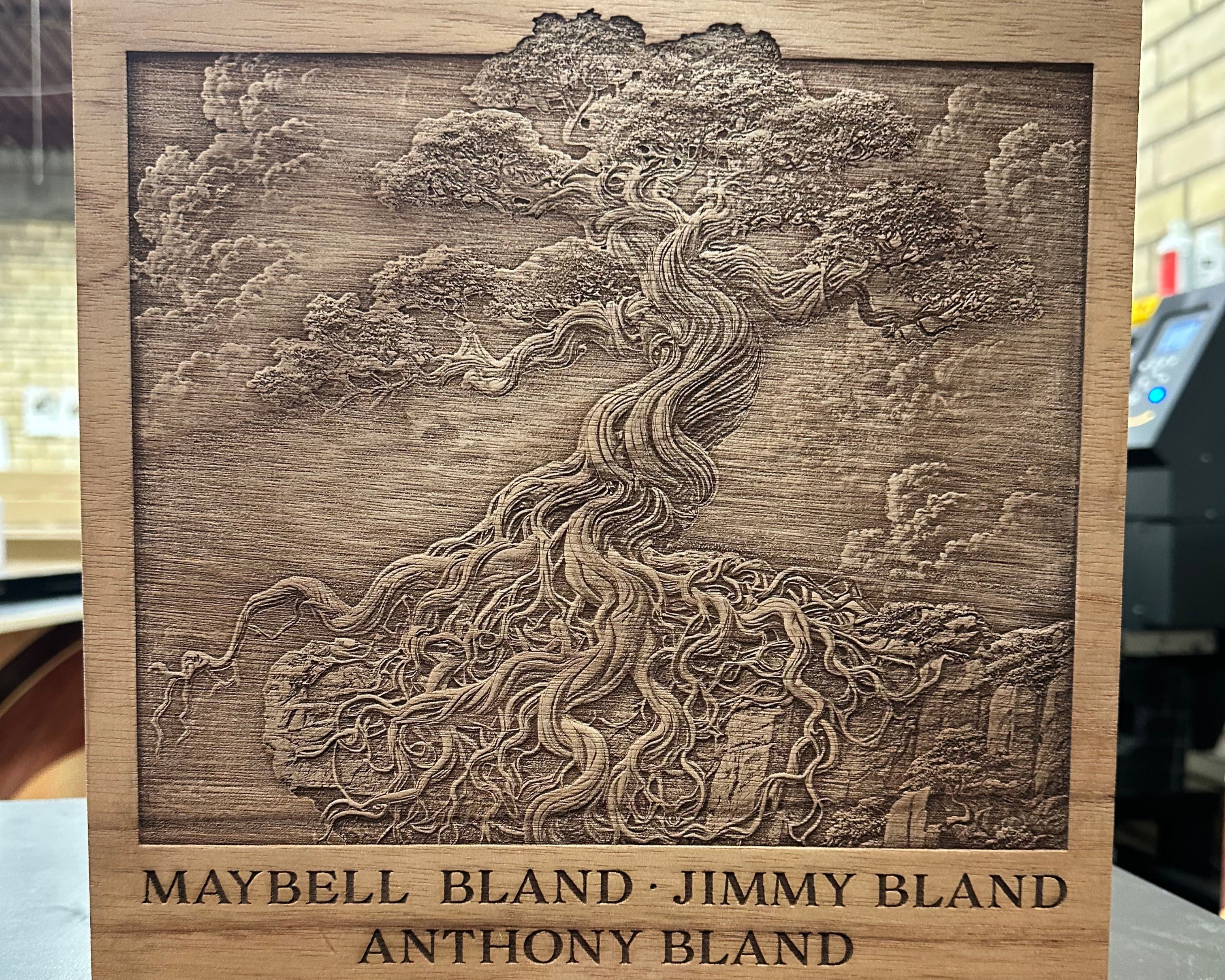 Wooden plaque with engraved design and names on a dark surface